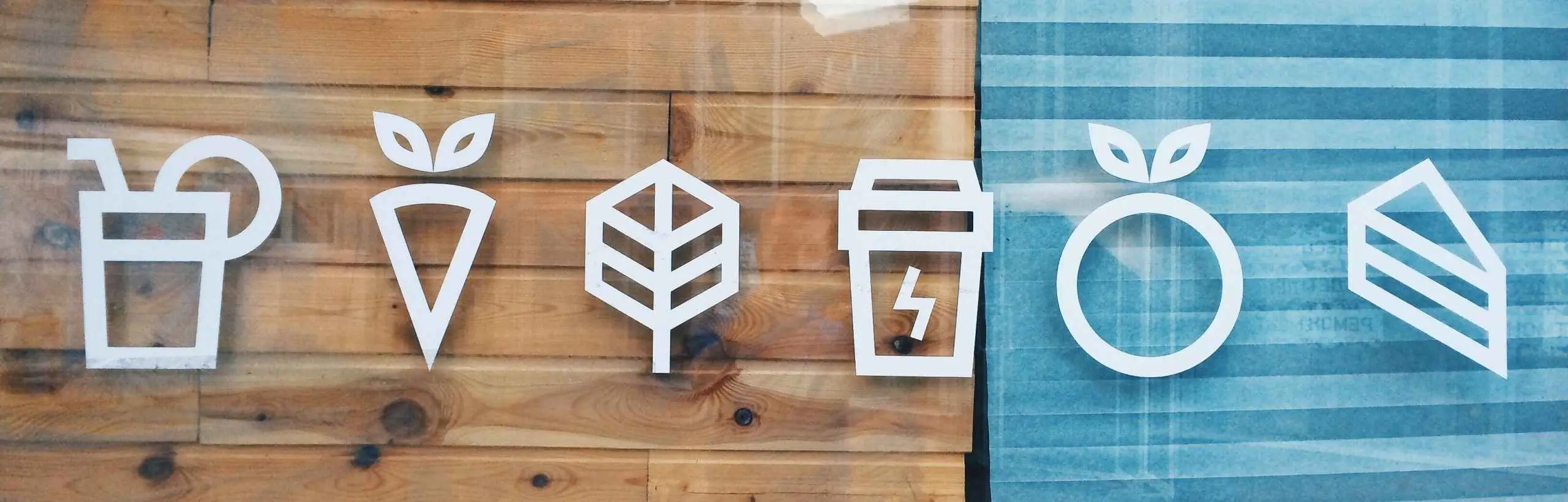 Minimale weiße Food-and-Drink-Icons auf Holz- und blauen Paneelen, die einheitliche Markendesignelemente und Logostil veranschaulichen