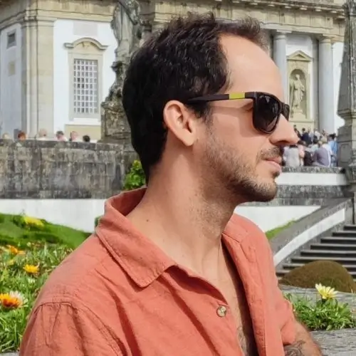 Mauricio, Automatisierungsexperte bei AkiByte, mit Sonnenbrille und orangefarbenem Hemd vor einem historischen Gebäude