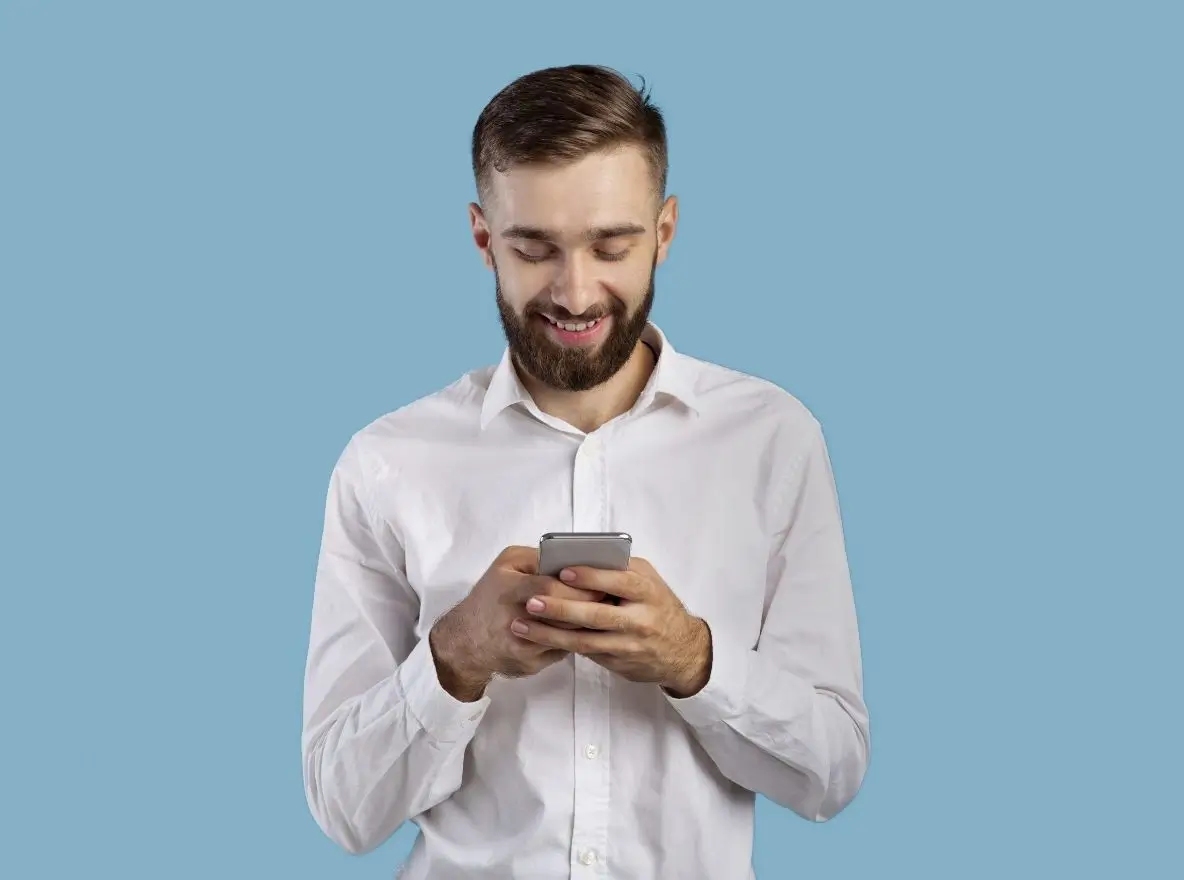 Lächelnder Mann im weißen Hemd nutzt Smartphone vor hellblauem Hintergrund, steht für intuitive und benutzerfreundliche UX